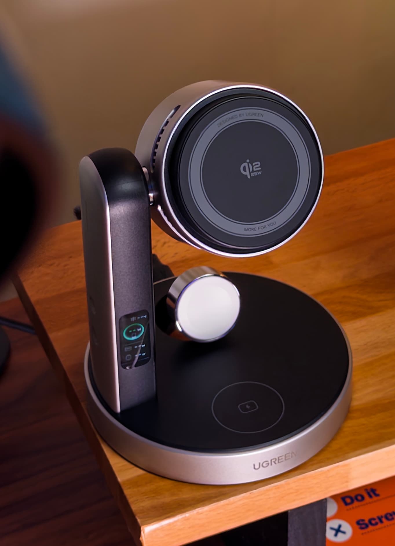 UGREEN MagFlow Pro on the edge of a wooden desk, angled to show its side display and watch charger