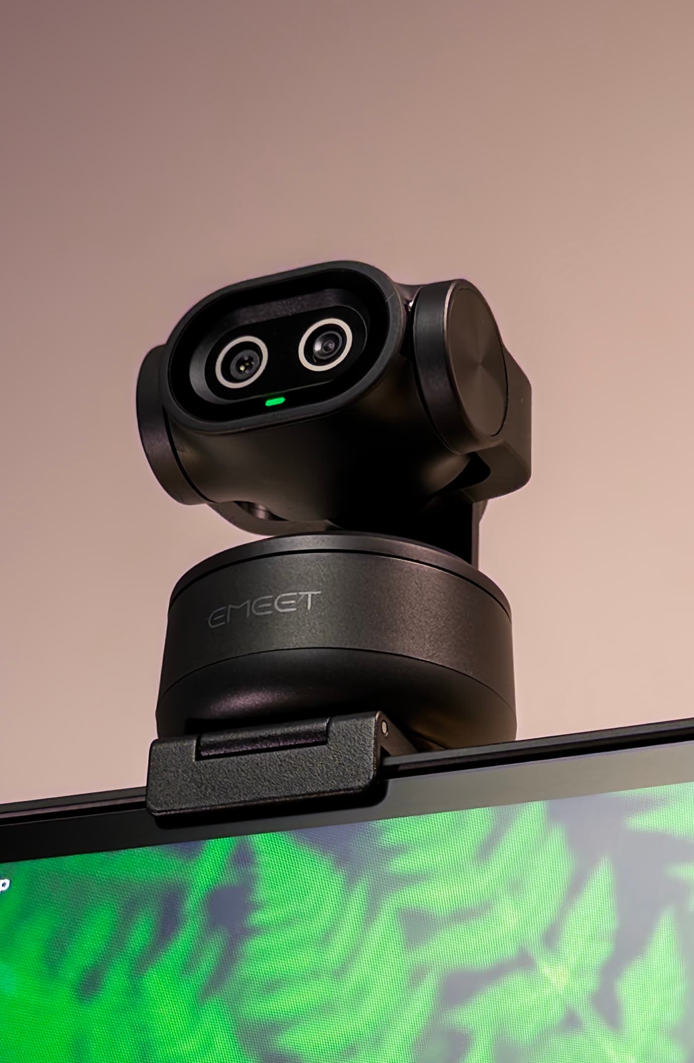 EMEET PIXY on a monitor, head turned to the left, showing its two lenses and green status light